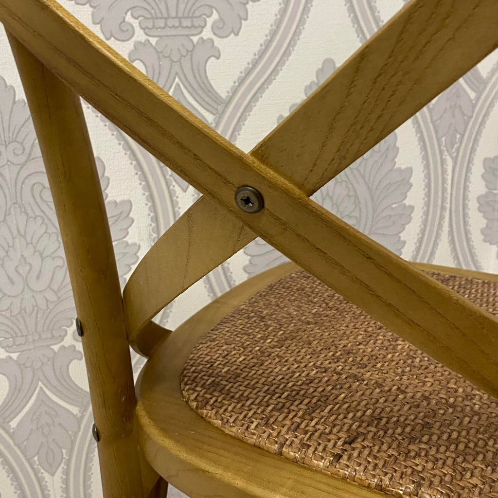 Cross-braced oak dining chair with woven seat and rounded corners, warm finish.
