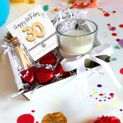 Gift hamper box with birthday card, candle, and red heart-shaped chocolates