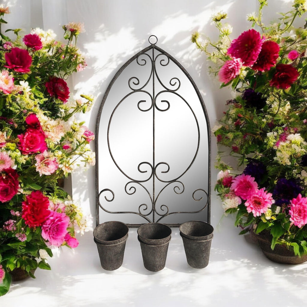 Arched metal wall mirror with ornate scroll frame and three planter pots along the bottom