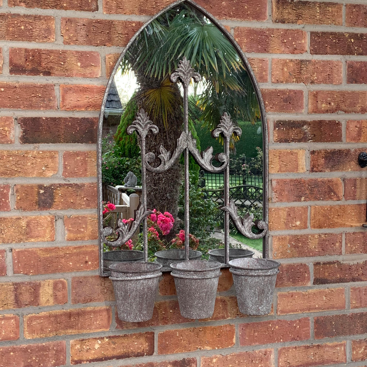 Arched metal wall mirror with triple planters, gray finish, with pink flowers and greenery