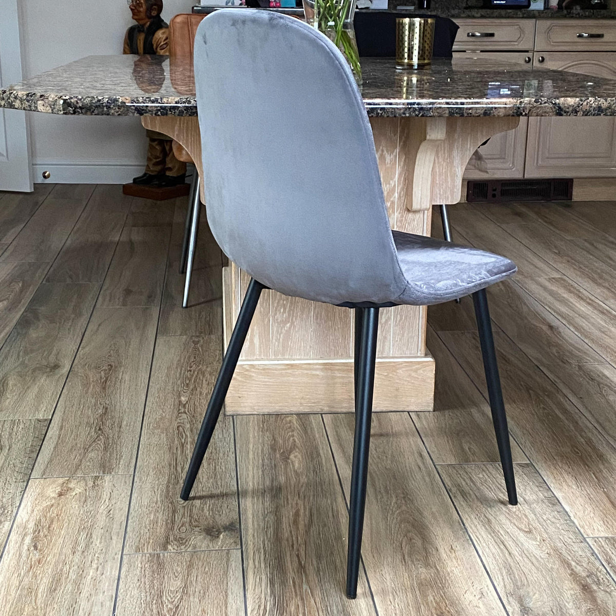 Grey velvet dining chair with black metal legs, three-quarter side view
