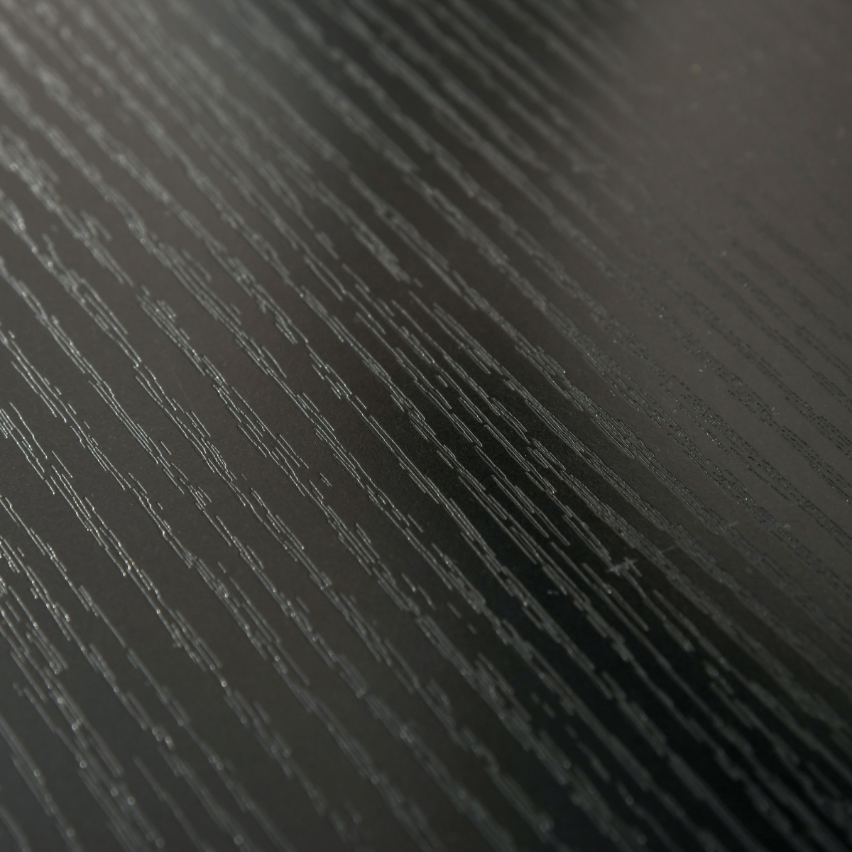 Textured dark surface of the monitor stand riser board with diagonal grain