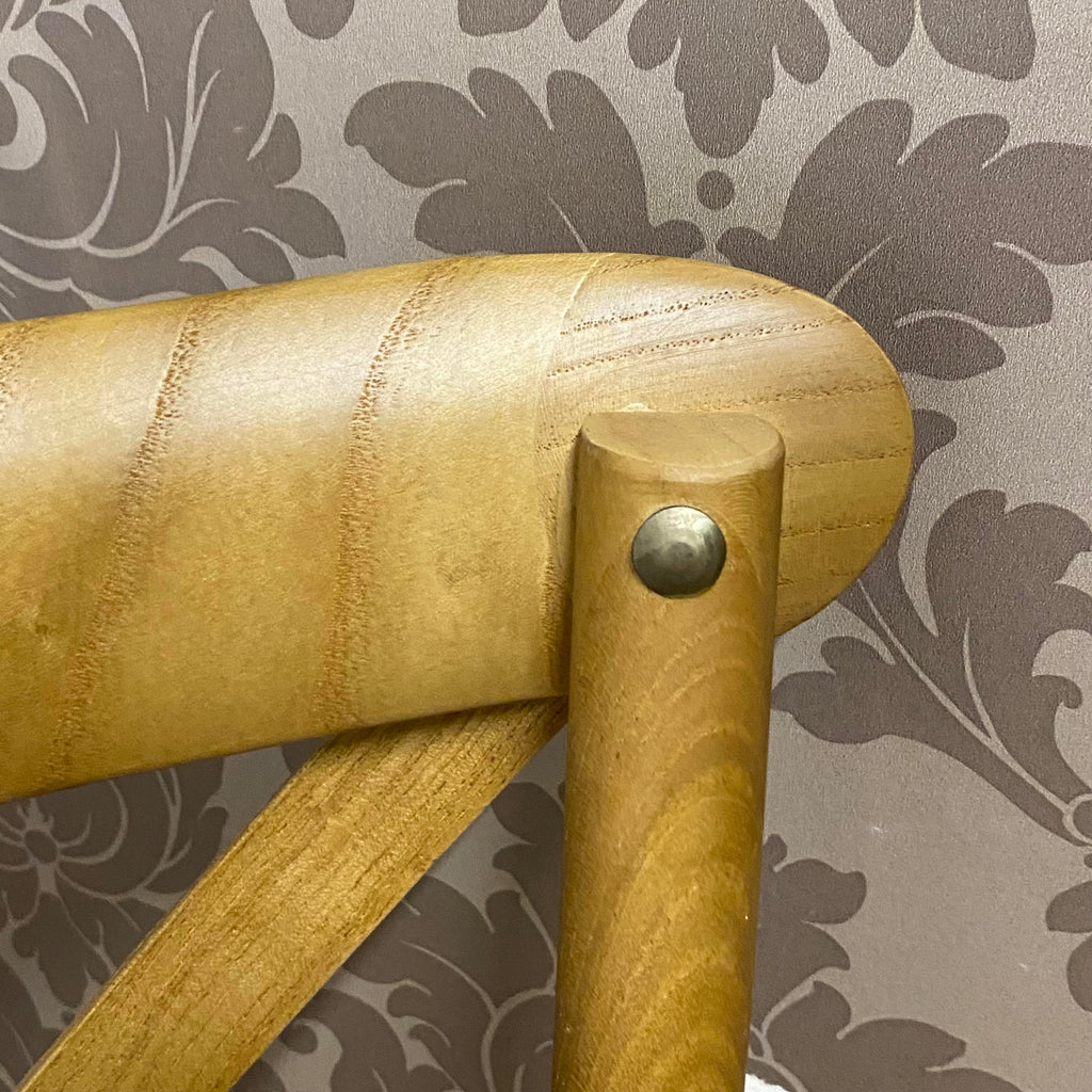 Curved oak chair arm with round metal knob, warm golden stained wood.