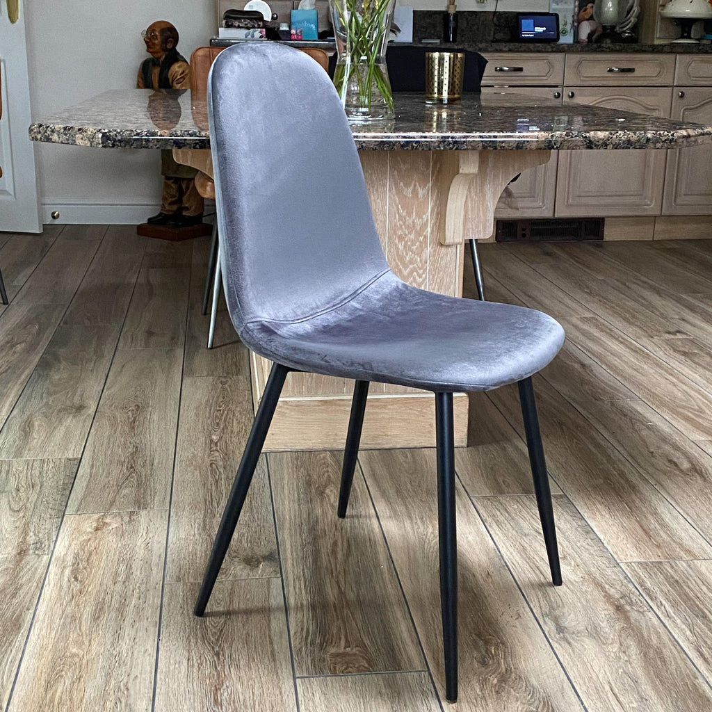 Grey velvet dining chair with black metal legs, side view with rounded back