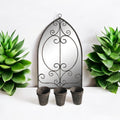 Arched metal wall mirror with floral scrollwork and three planter pots below
