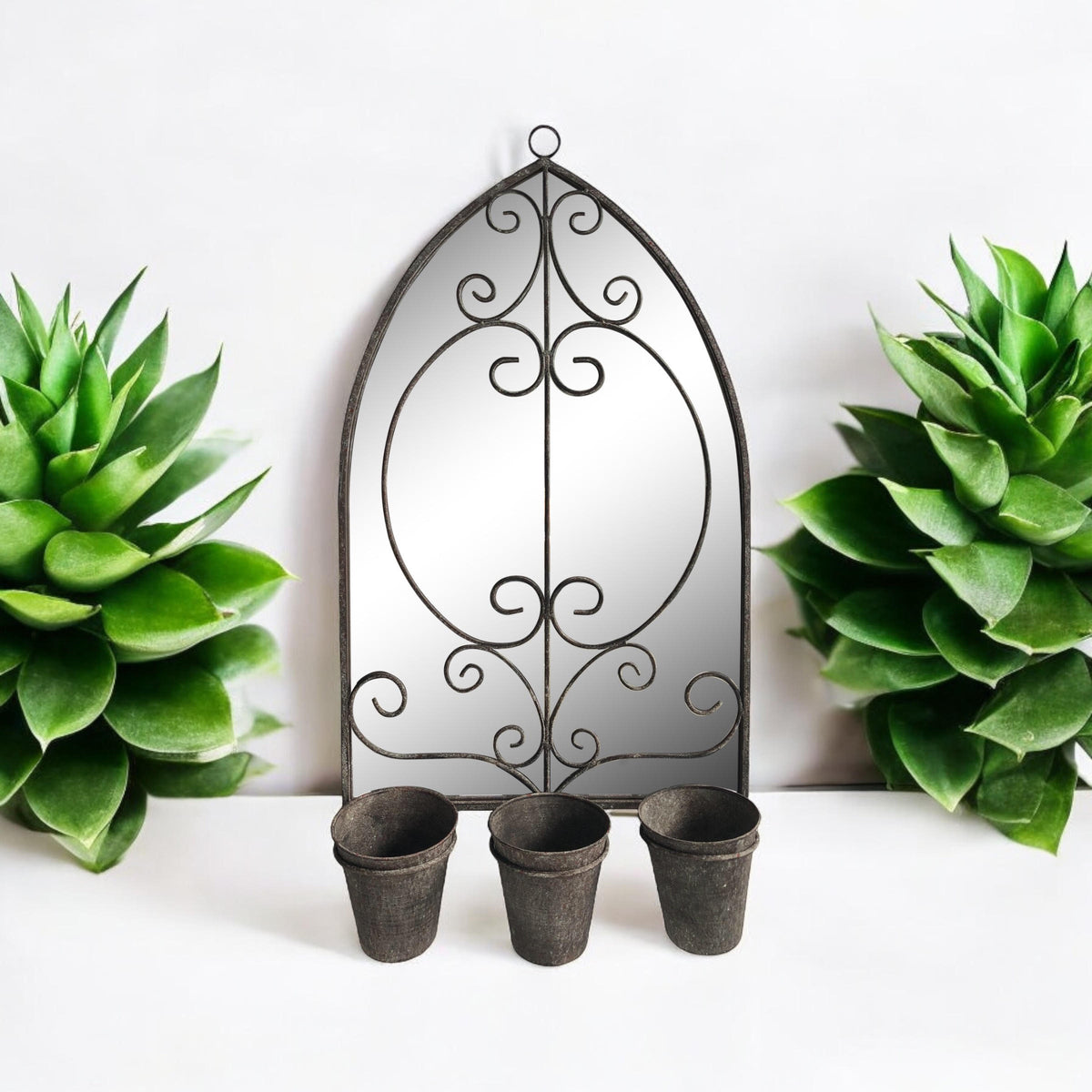 Arched metal wall mirror with floral scrollwork and three planter pots below