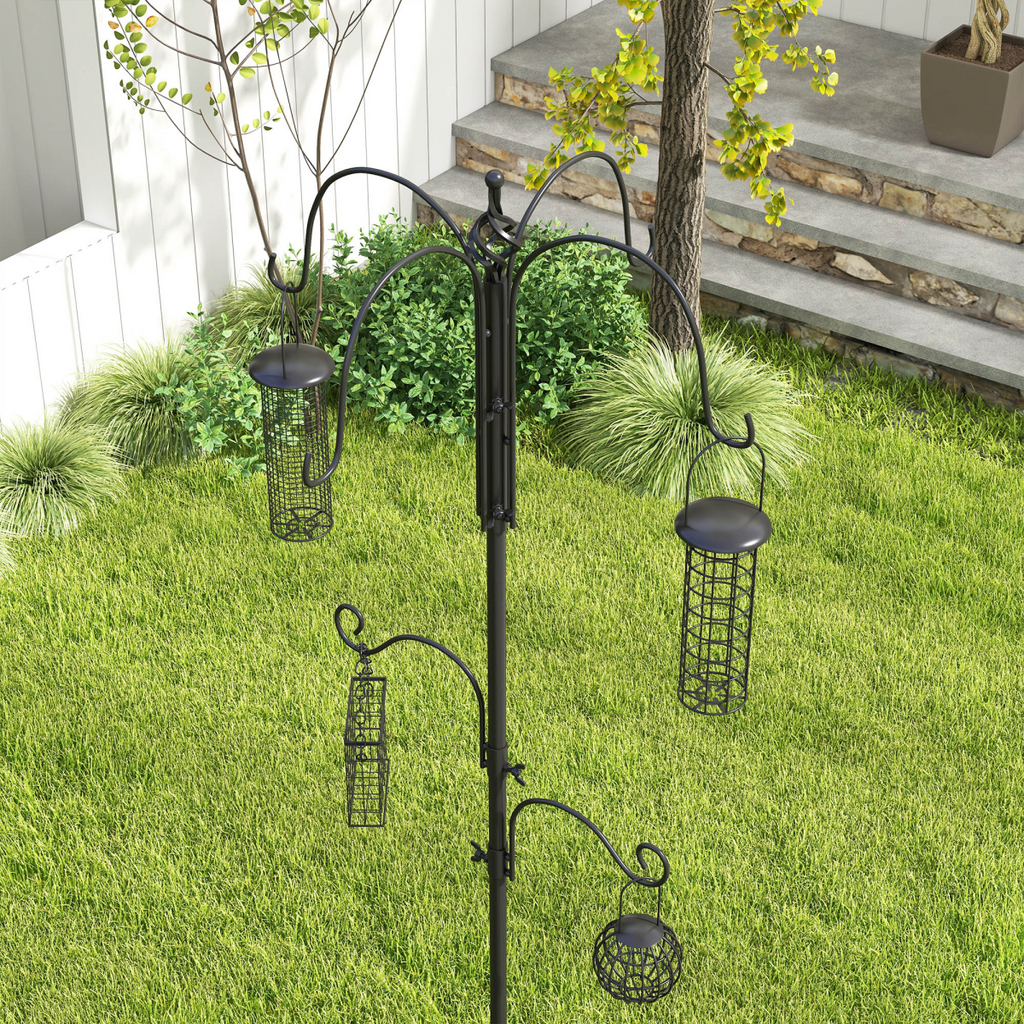 Black bird feeding station with multiple hanging wire feeders on backyard lawn