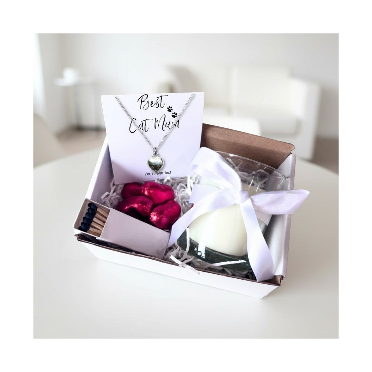 Cat gift hamper with heart necklace, white candle, red chocolates, and matchbox in box